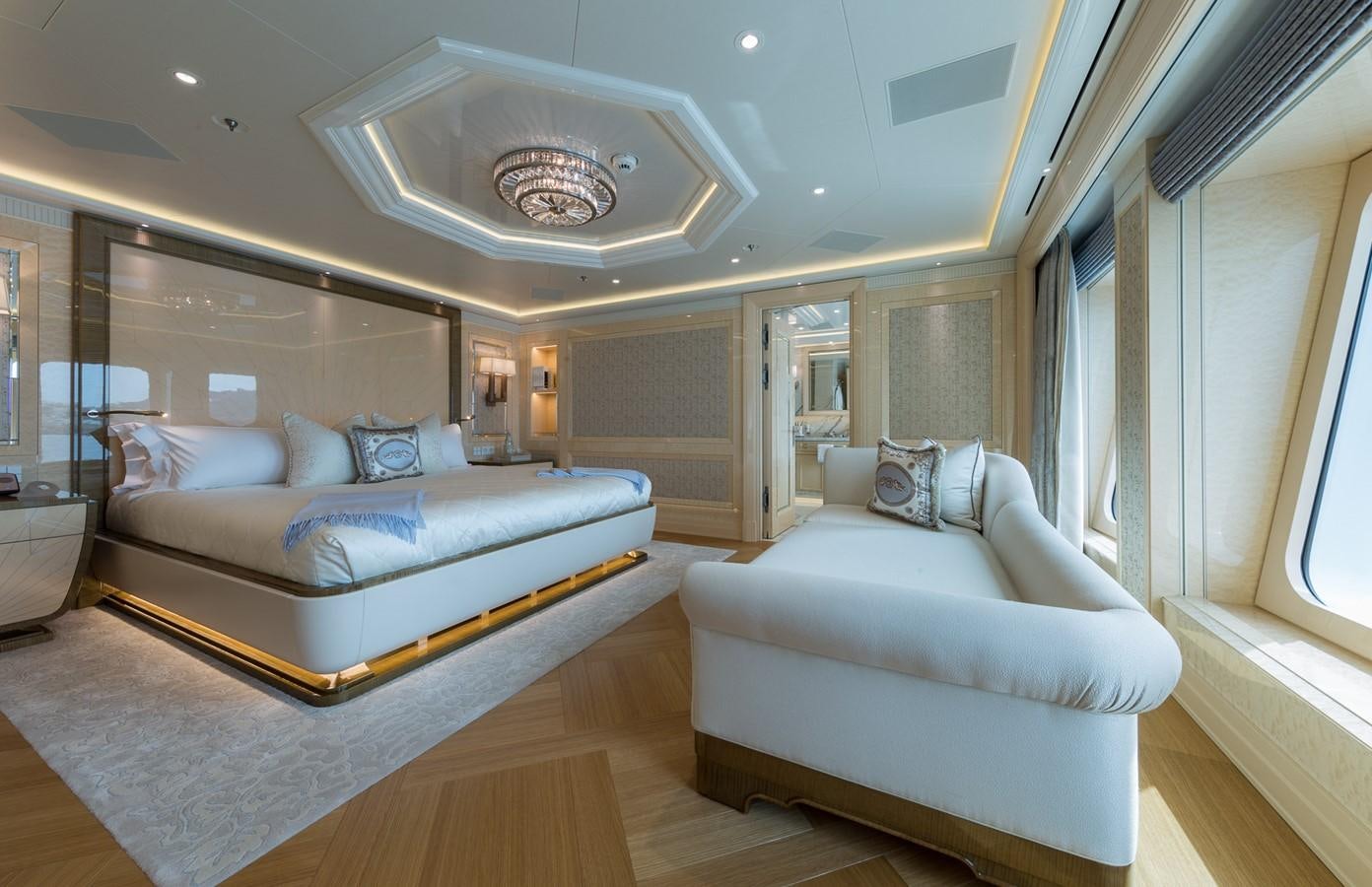 a large living room with a large bed and a large chandelier aboard PLVS VLTRA Yacht for Sale