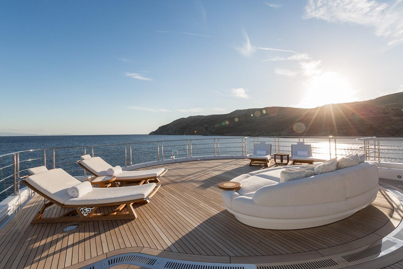 a deck with lounge chairs on it and a body of water in the background aboard PLVS VLTRA Yacht for Sale