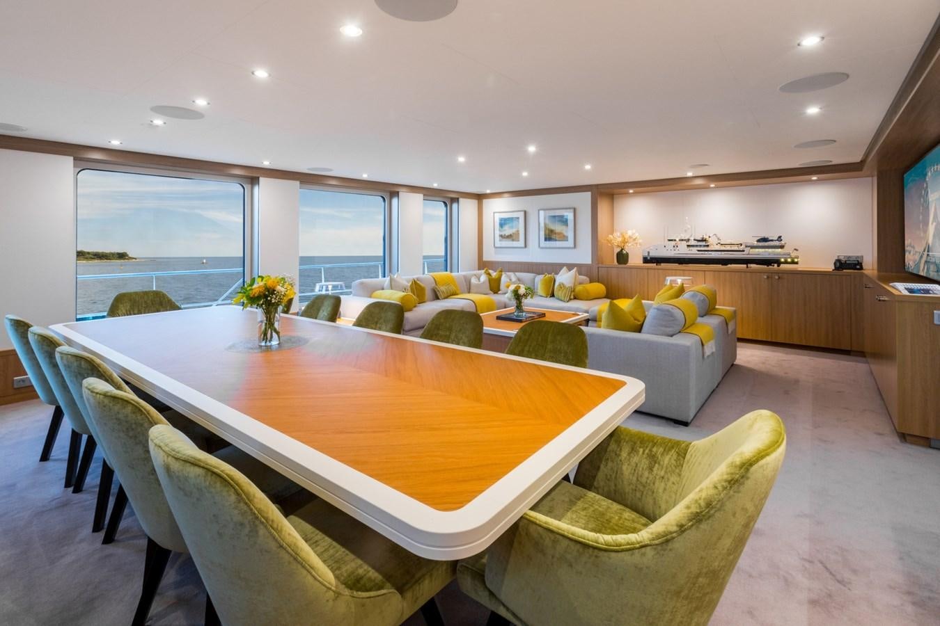 a large living room with a table and chairs aboard GAME CHANGER Yacht for Sale