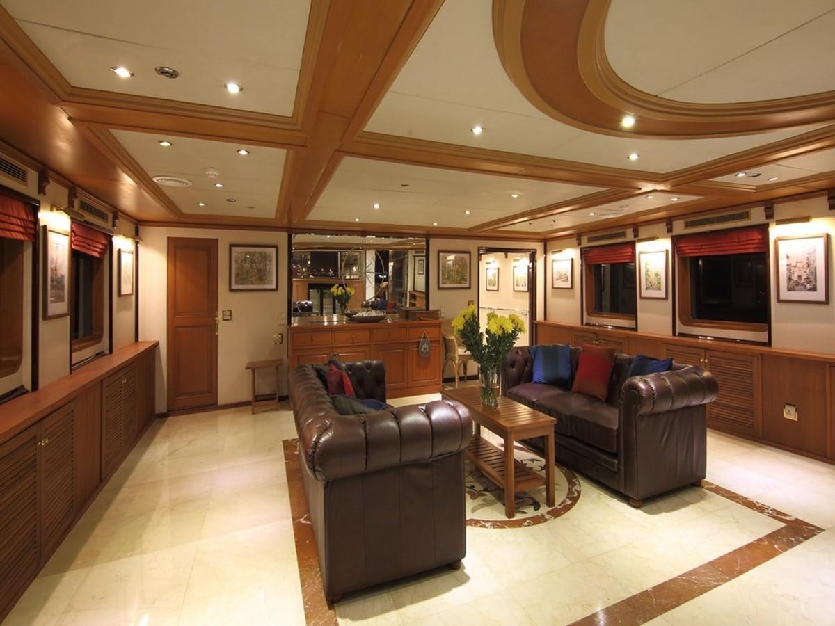 a living room with a leather couch and a wood table aboard ANDAMAN EXPLORER Yacht for Sale
