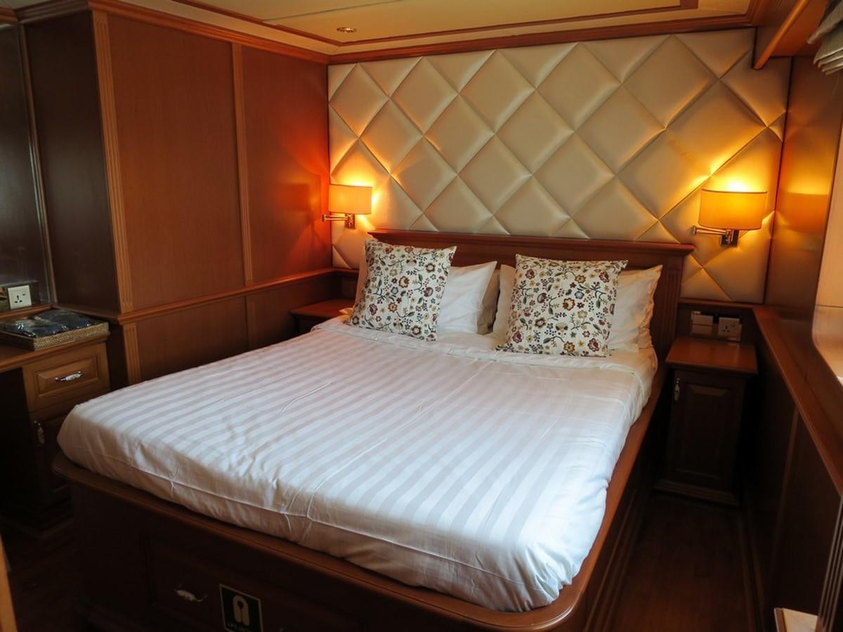 a bed with a white comforter aboard ANDAMAN EXPLORER Yacht for Sale