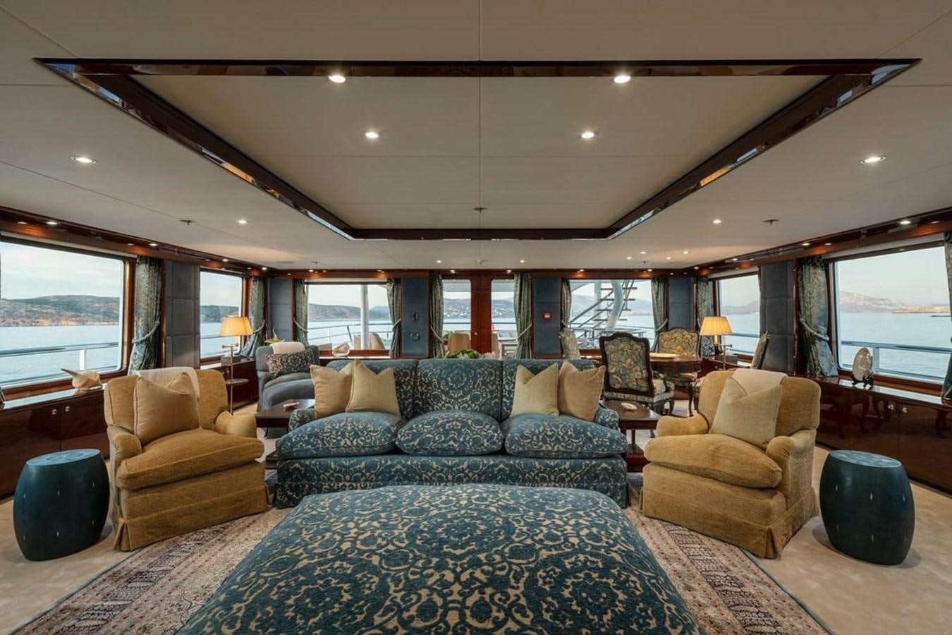 a living room with a large blue couch and a large window aboard LA FAMILIA Yacht for Sale