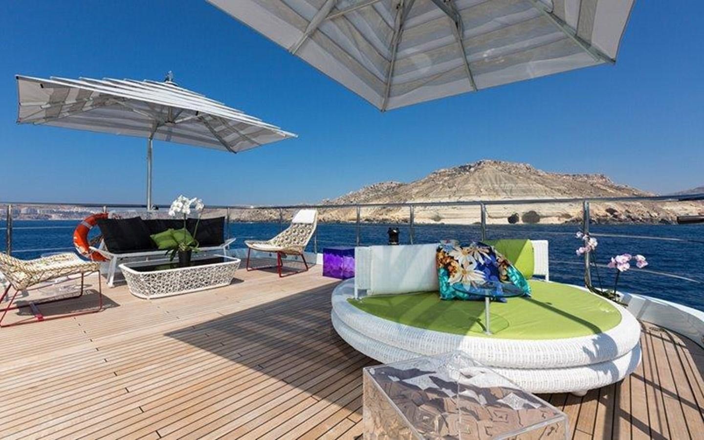 a lounge chair and umbrella on a deck with a view of the ocean aboard OCEAN PARADISE Yacht for Sale