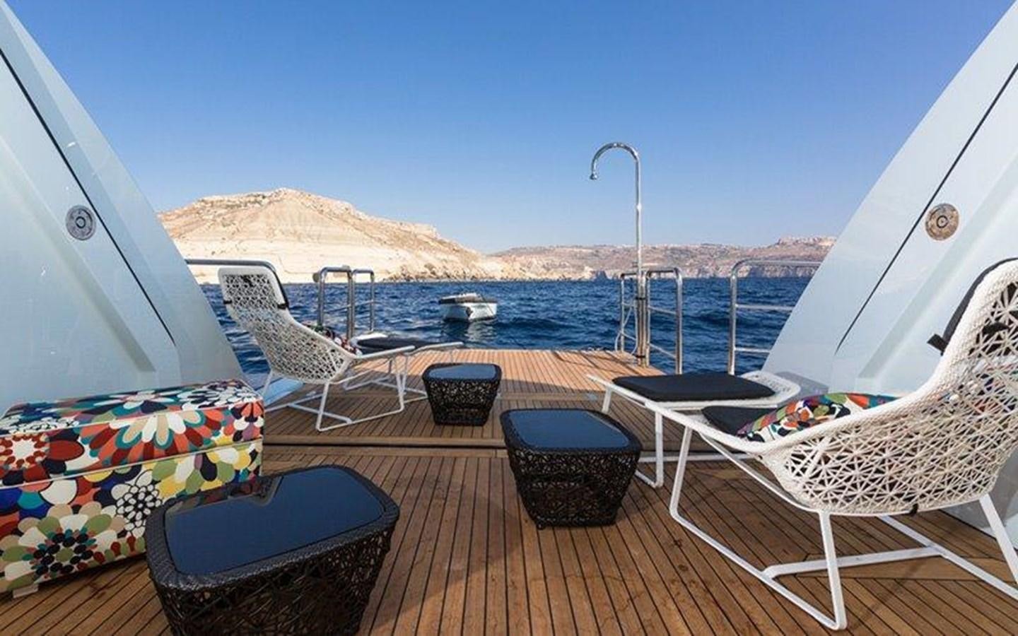 a deck with chairs and a body of water in the background aboard OCEAN PARADISE Yacht for Sale