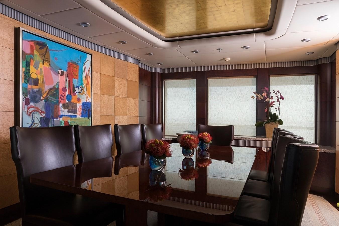 a room with a table chairs and a painting on the wall aboard FORTUNATE SUN Yacht for Sale