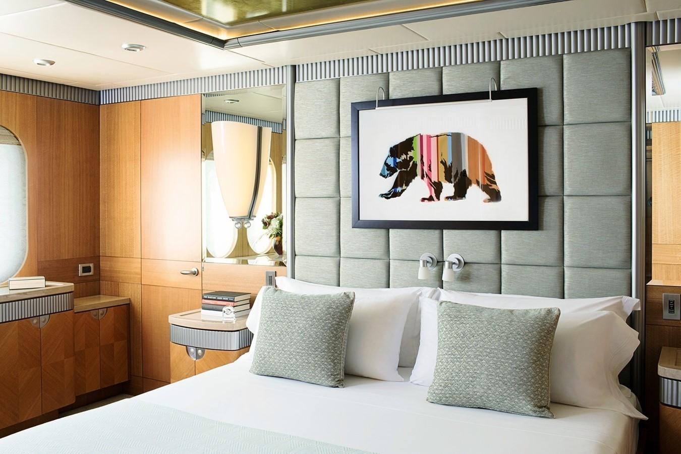 a bed with pillows and a painting above it aboard FORTUNATE SUN Yacht for Sale