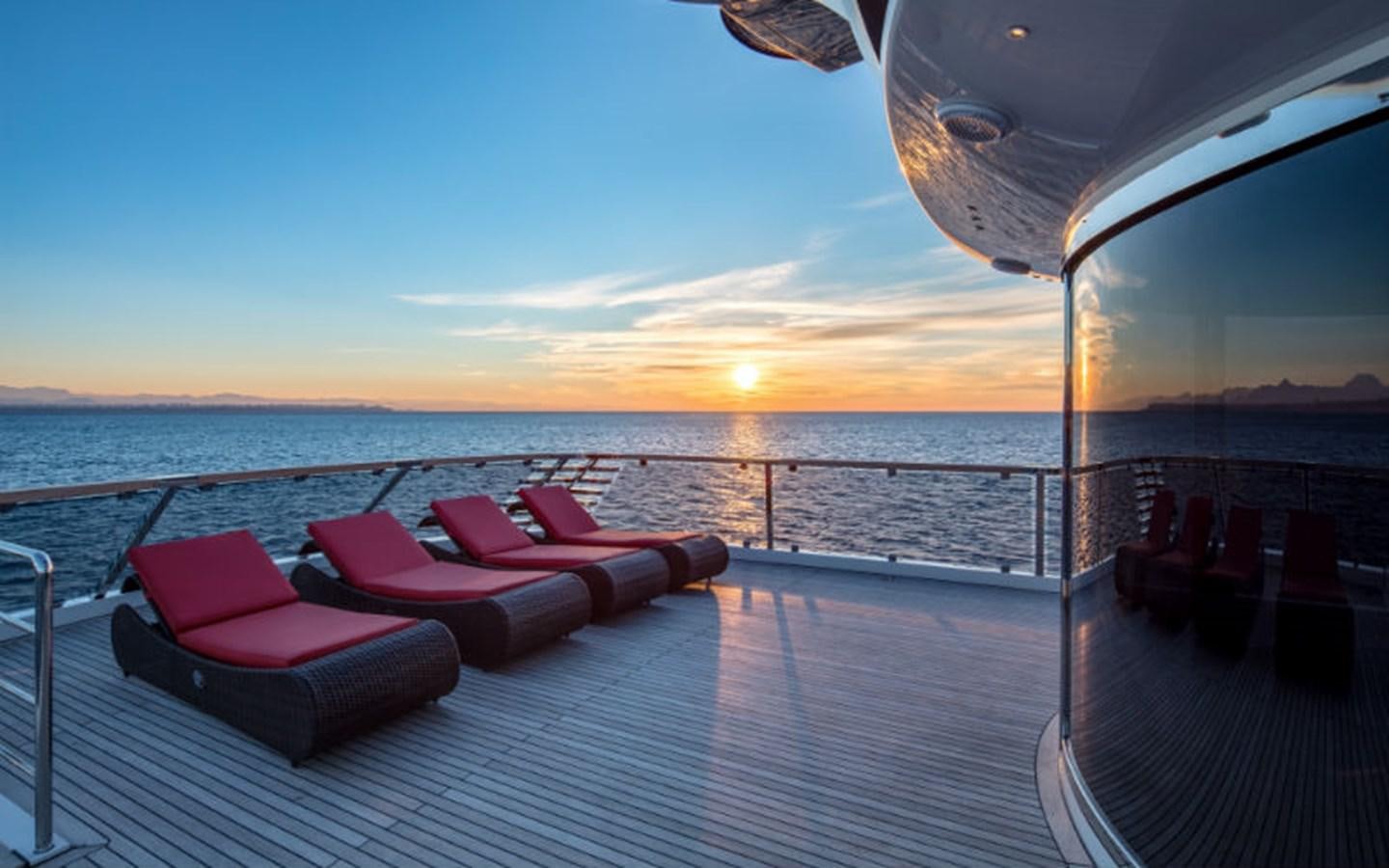 a deck with chairs on it and the sun setting in the background aboard EUPHORIA Yacht for Sale