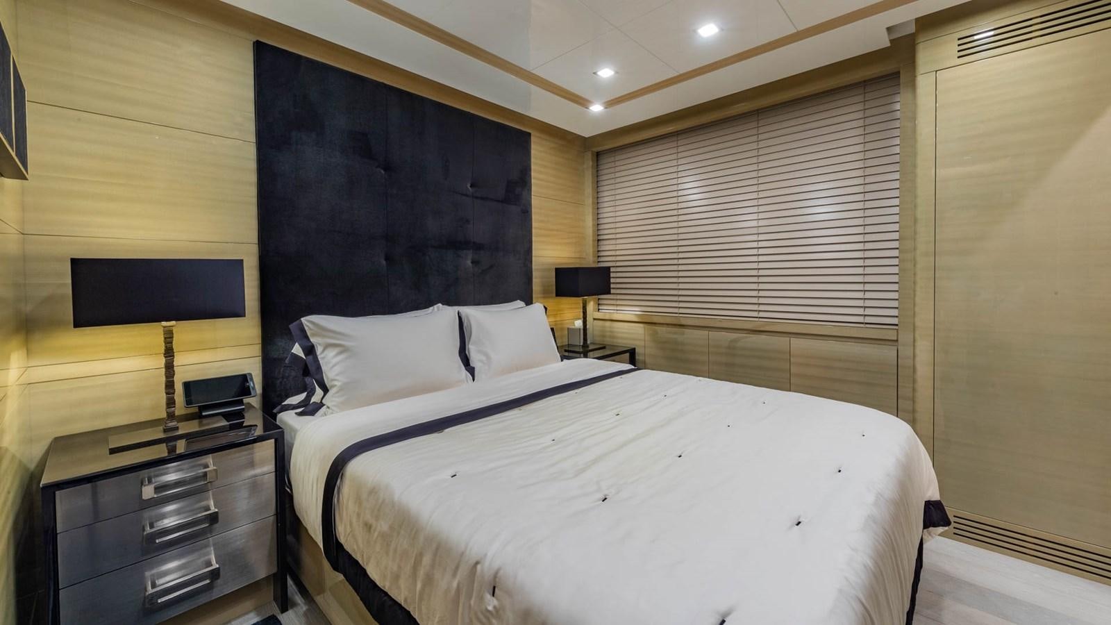a bed with a white sheet and pillows in a room with a television aboard APRICITY Yacht for Sale