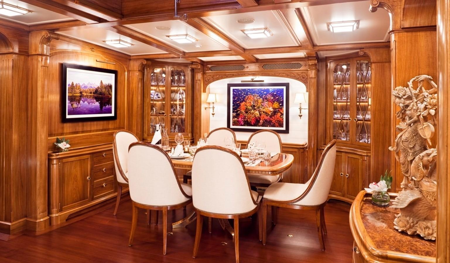 a room with a table chairs and a painting on the wall aboard HANUMAN Yacht for Sale