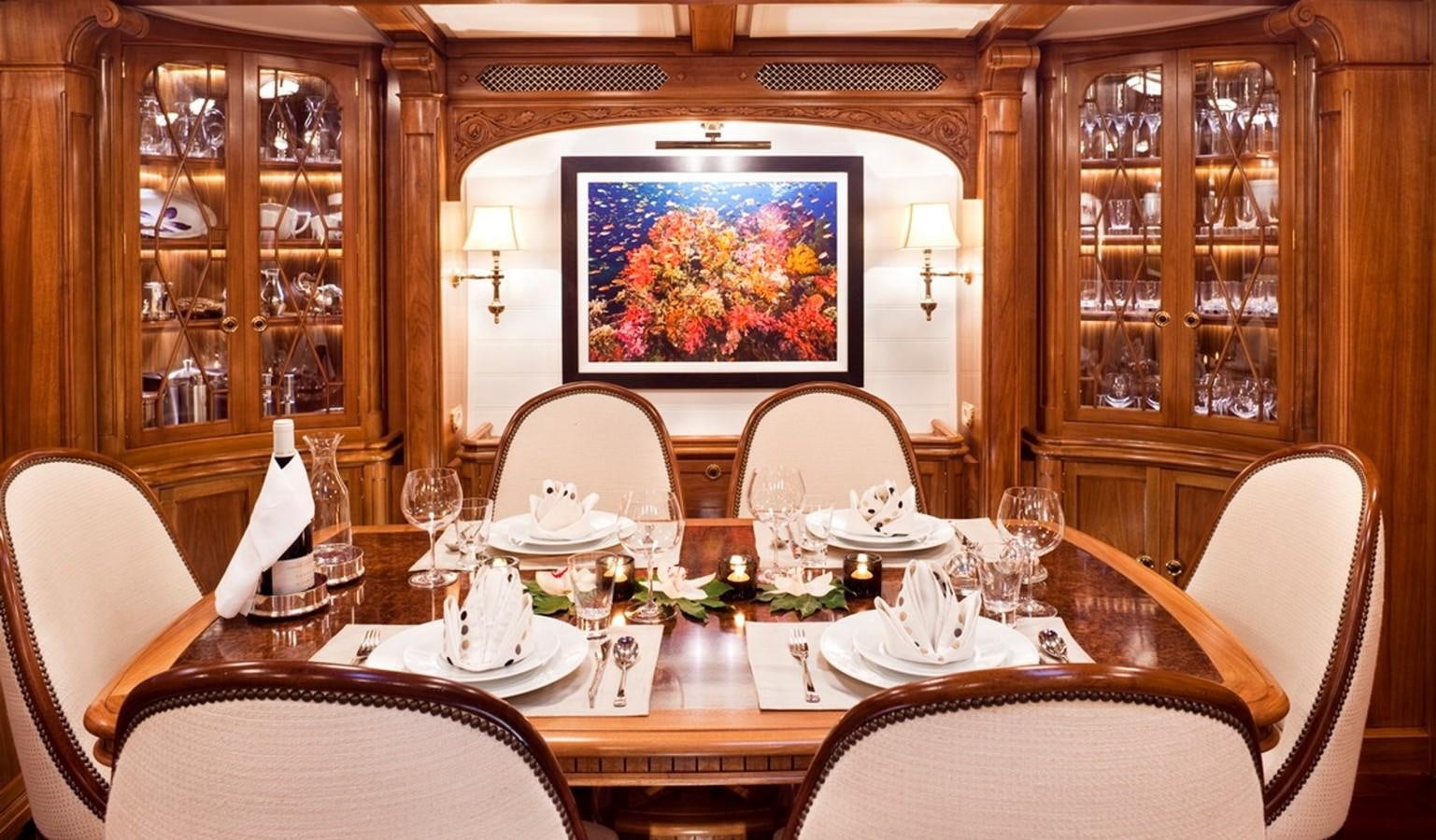 a dining room table with a painting on the wall aboard HANUMAN Yacht for Sale