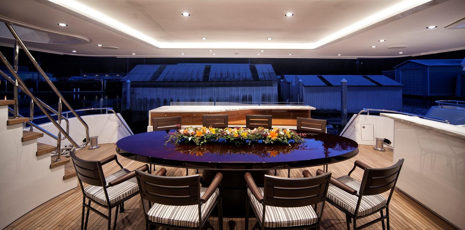 a pool table with chairs and a table with flowers on it aboard PEPPER XIII Yacht for Sale