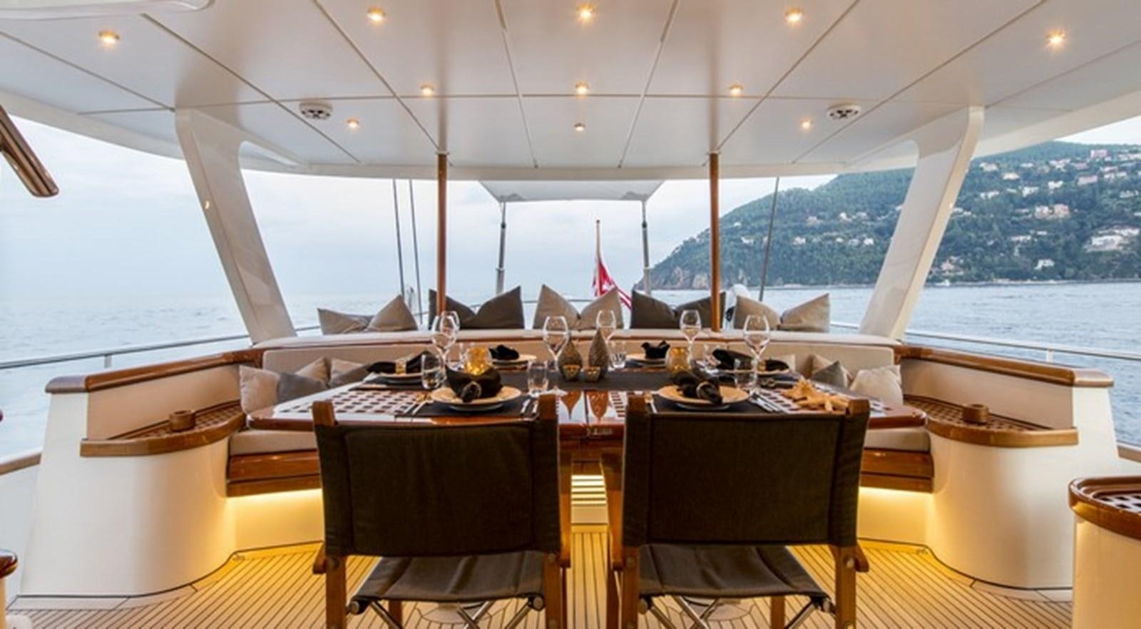 a table with chairs and a view of the ocean aboard CORTO MALTESE Yacht for Sale