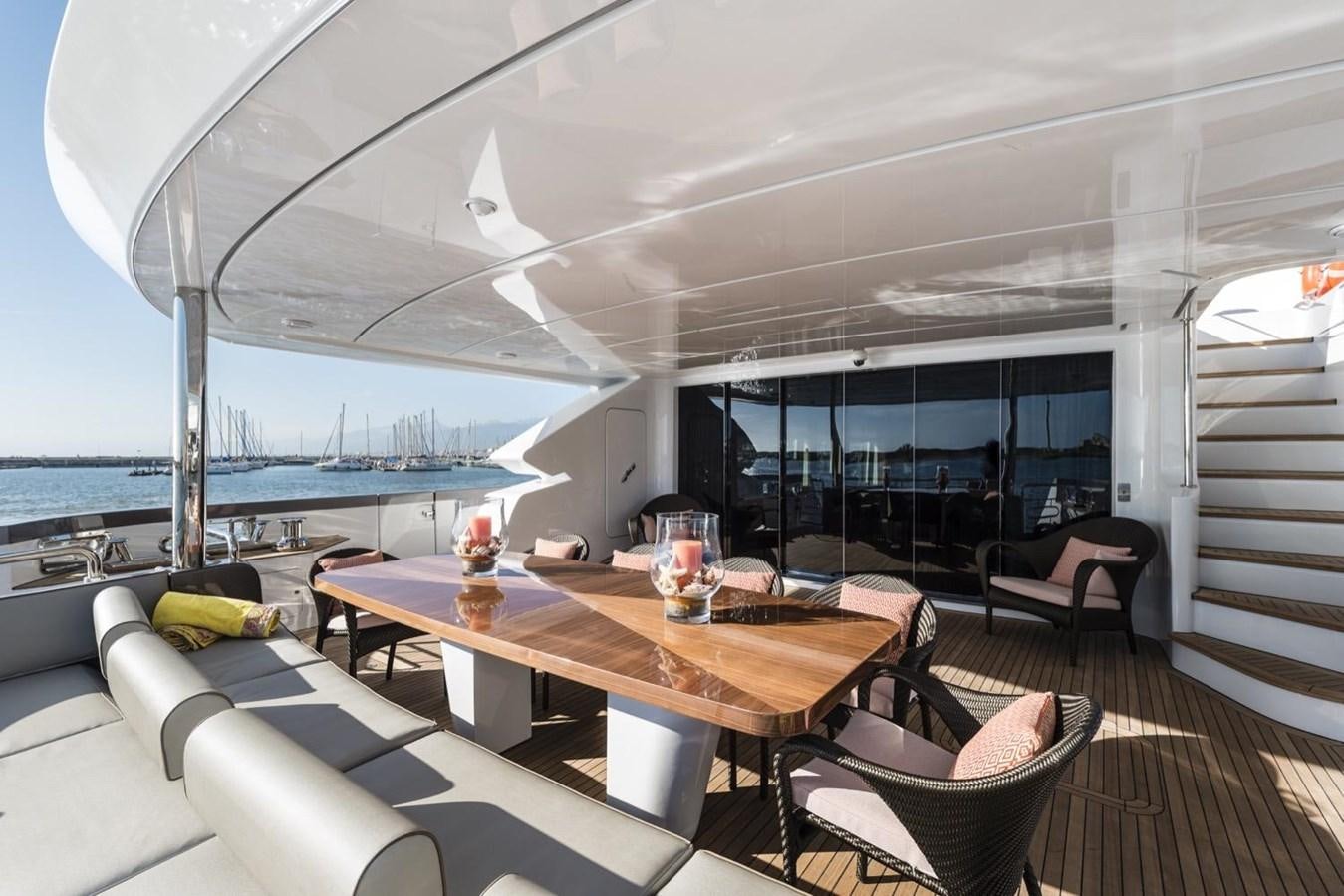 a table with a glass window overlooking a beach aboard HARMONY Yacht for Sale