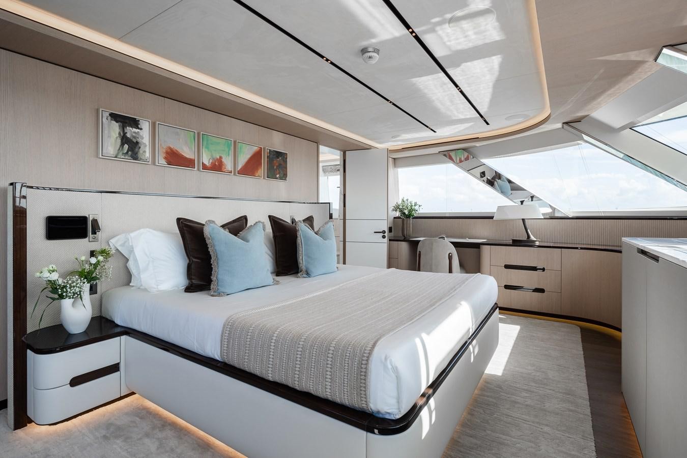 a bedroom with a bed and a desk aboard MOONEN 110 MUSTIQUE Yacht for Sale