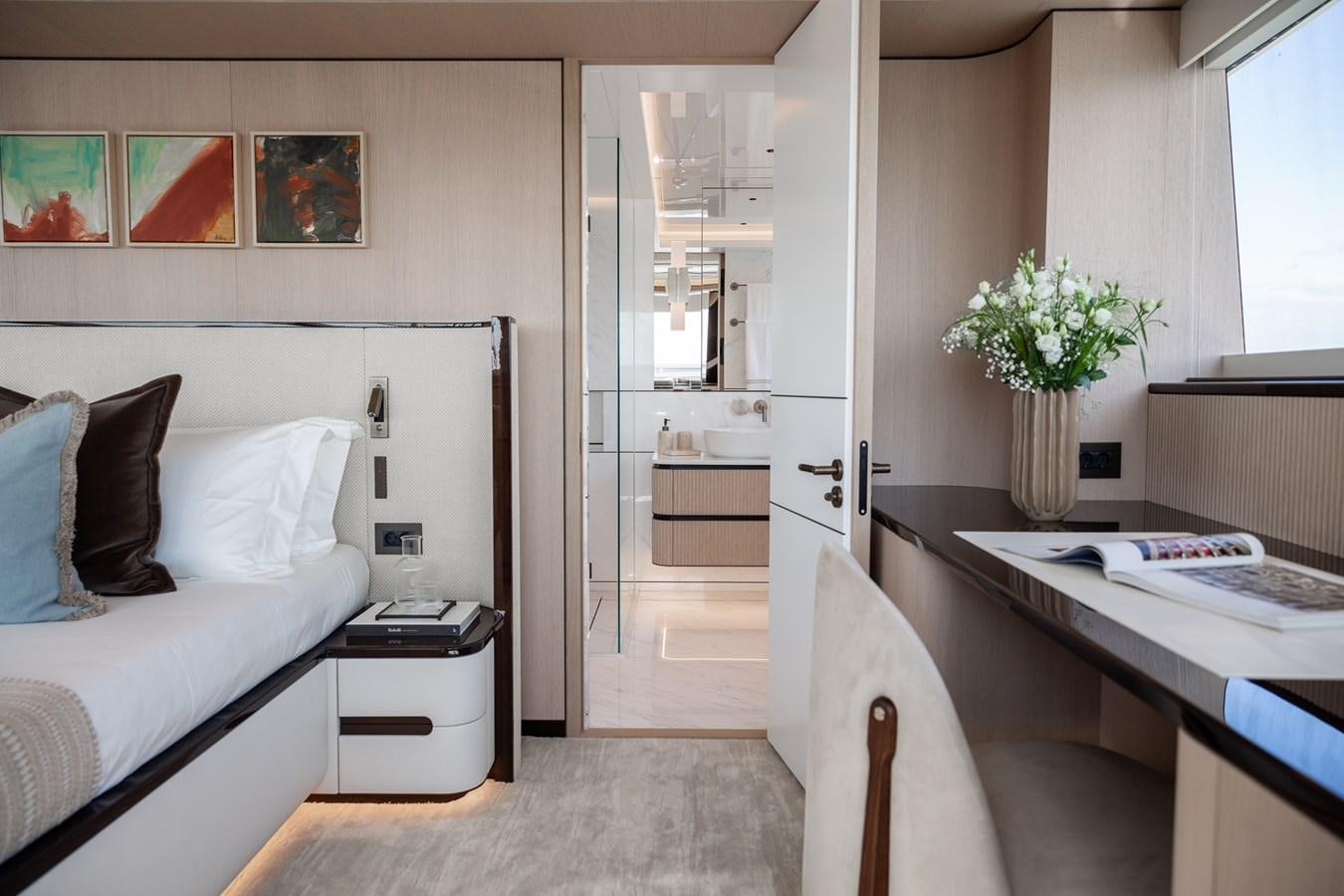 a bedroom with a bed desk and a closet aboard MOONEN 110 MUSTIQUE Yacht for Sale