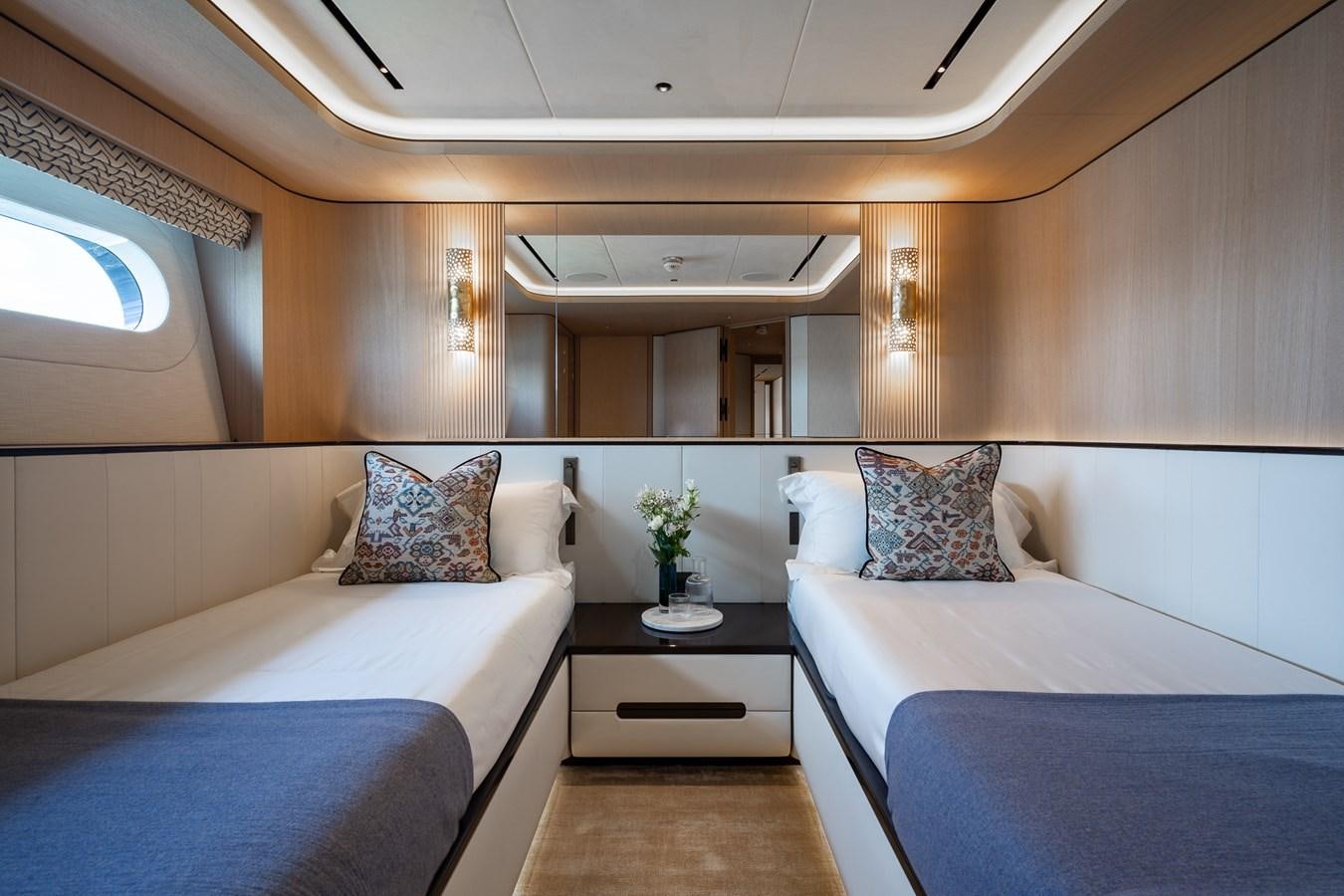 a room with beds and a table aboard MOONEN 110 MUSTIQUE Yacht for Sale