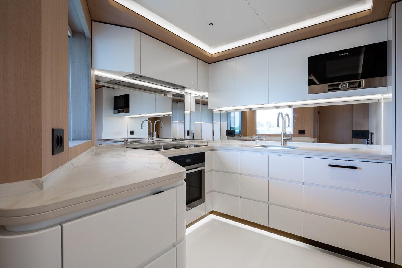 a kitchen with white cabinets aboard MOONEN 110 MUSTIQUE Yacht for Sale