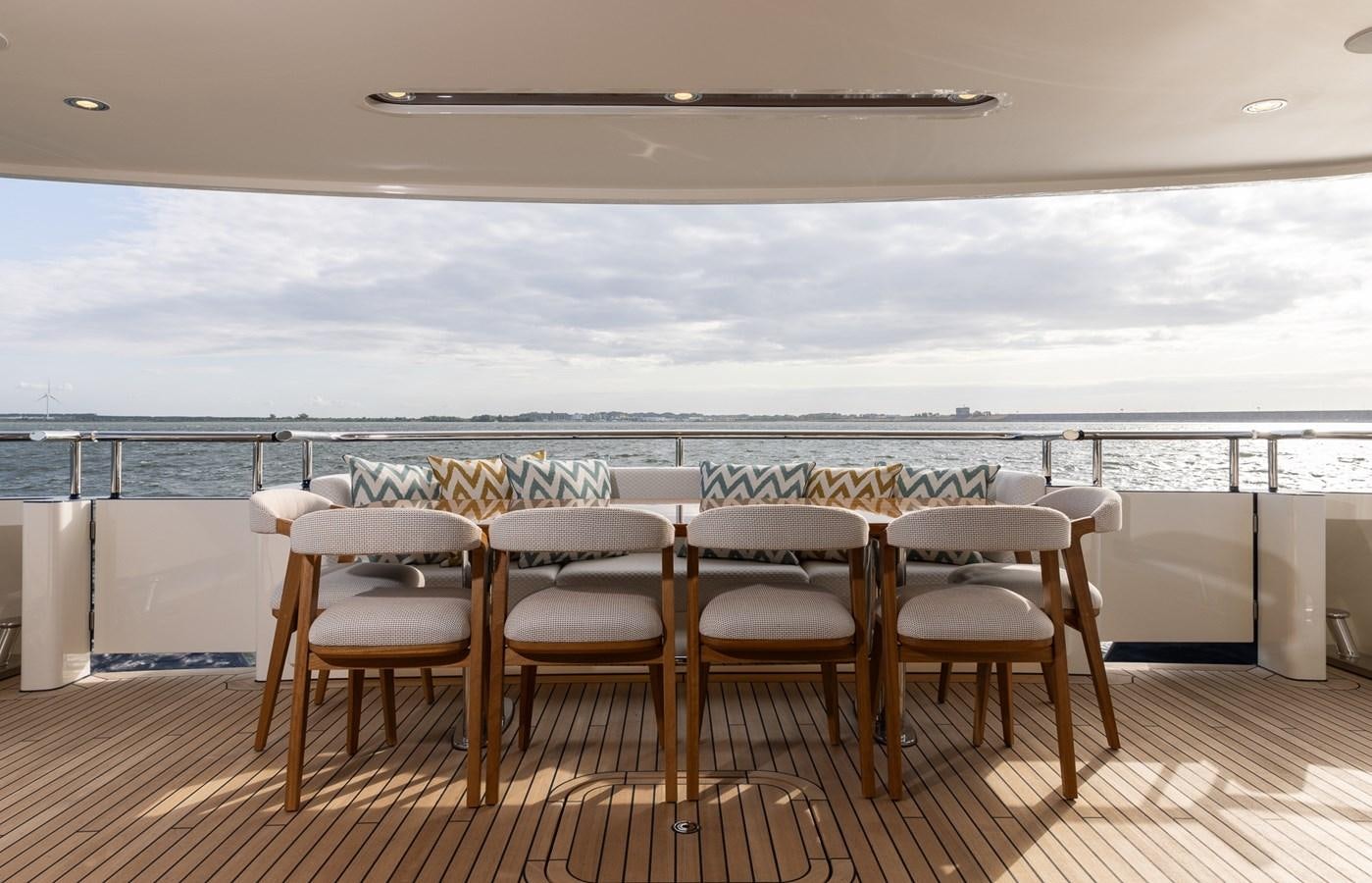 a table and chairs on a deck overlooking a body of water aboard MOONEN 110 MUSTIQUE Yacht for Sale