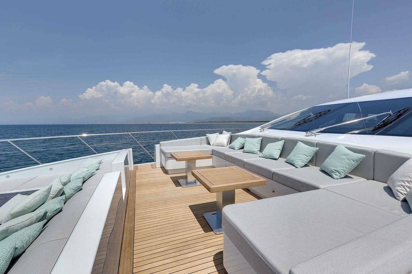 a deck with chairs and tables on it by the ocean aboard MANGUSTA 110 - CAREFULLY USED Yacht for Sale