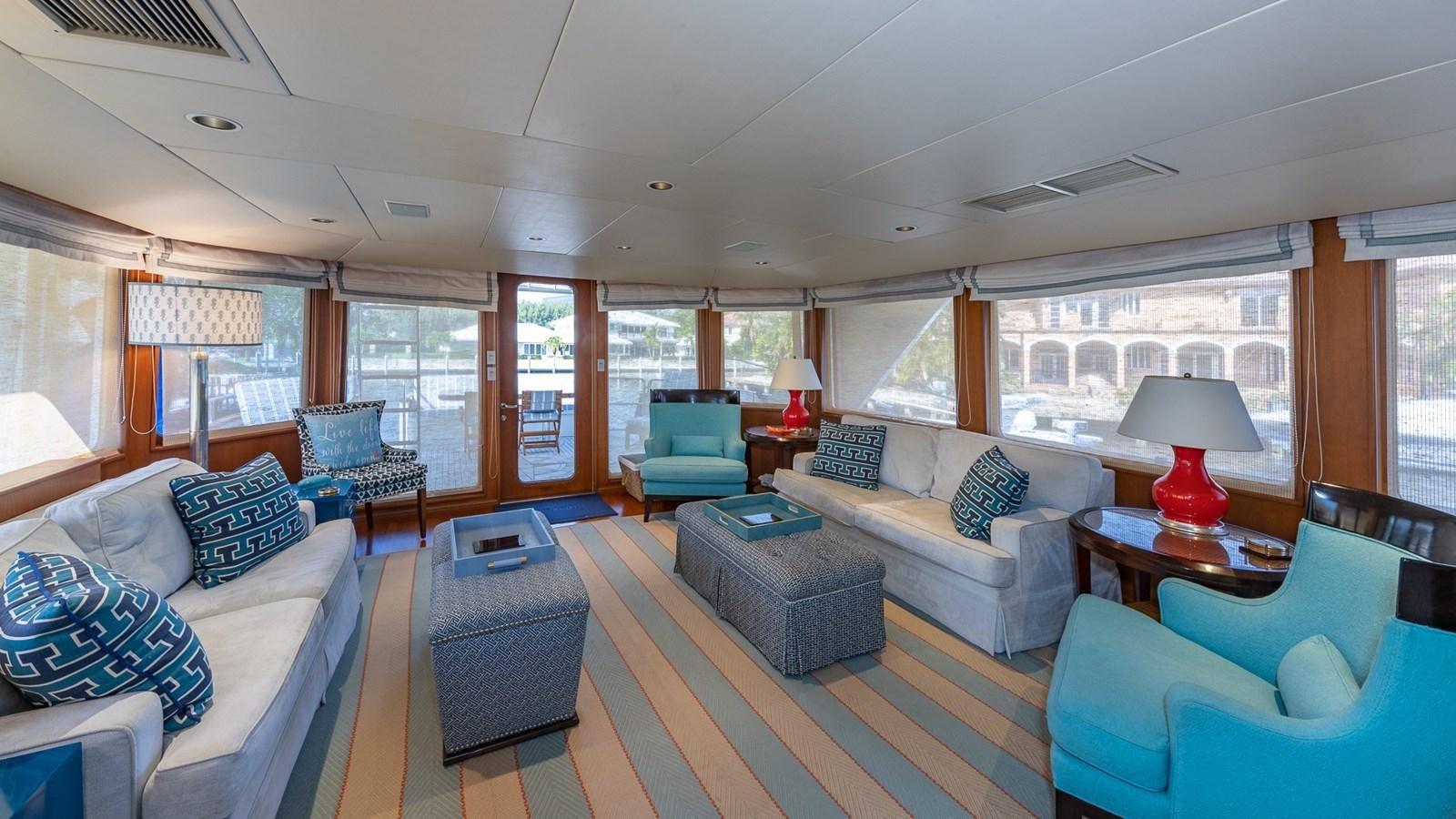 a living room with blue chairs and a table aboard SEAQUEL Yacht for Sale