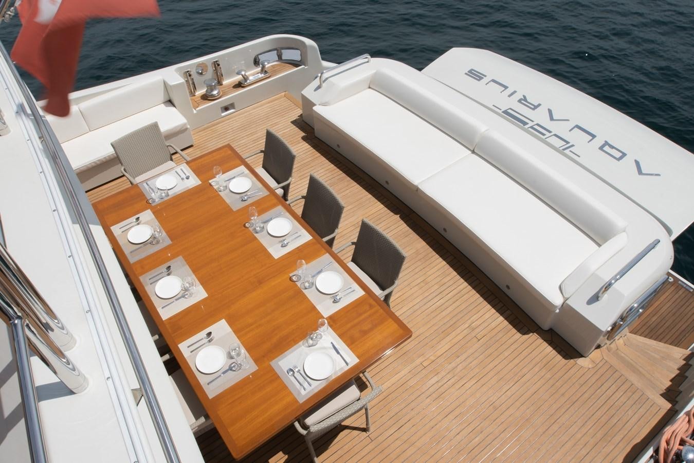 a wooden table with chairs and a piano on it aboard AQUARIUS Yacht for Sale
