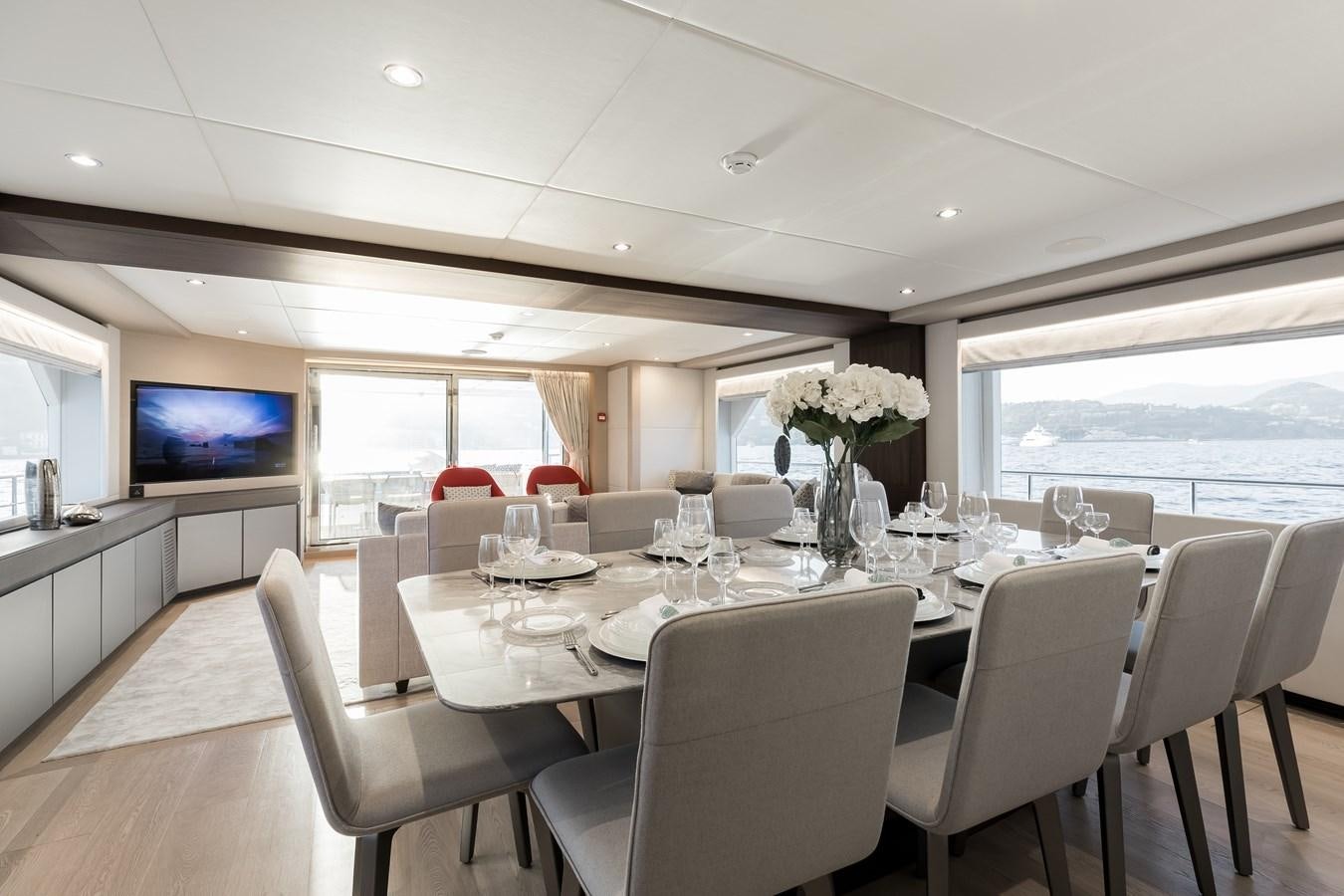 a dining table with white chairs and white tablecloths aboard JEWEL Yacht for Sale