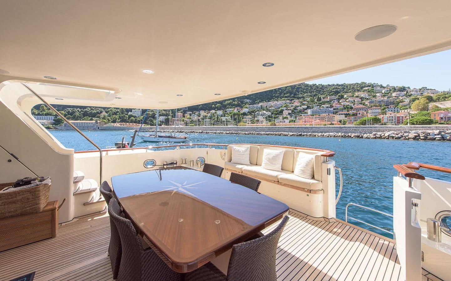 a room with a table and chairs on a deck overlooking a city aboard LITTLE PERLE Yacht for Sale