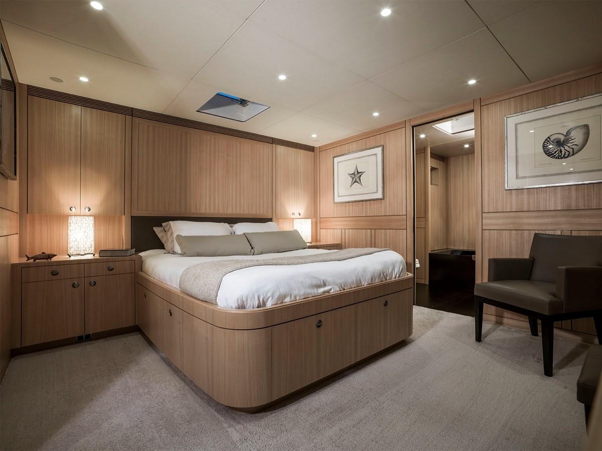 a bedroom with a bed and a chair aboard SATU Yacht for Sale