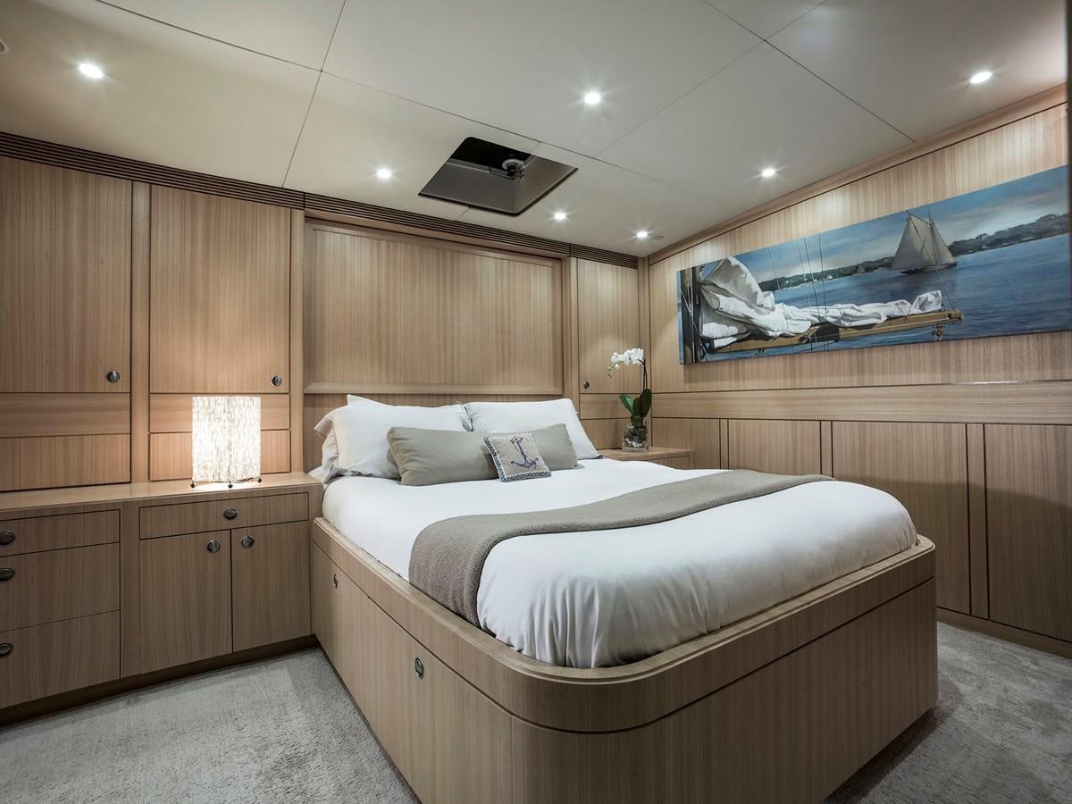 a bedroom with a bed and a wood wall aboard SATU Yacht for Sale