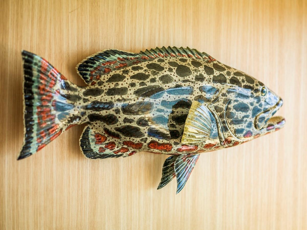 a colorful pillow on a wood surface aboard SATU Yacht for Sale