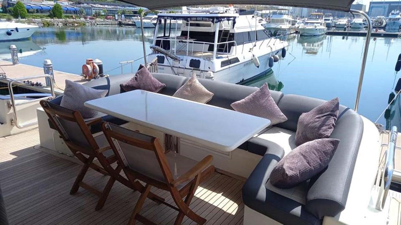 a deck with a table and chairs on it by a body of water aboard AEGINA Yacht for Sale