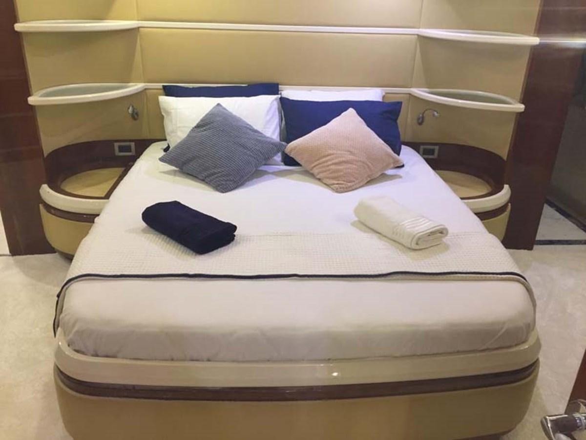 a bed with a white cover and blue pillows aboard AEGINA Yacht for Sale