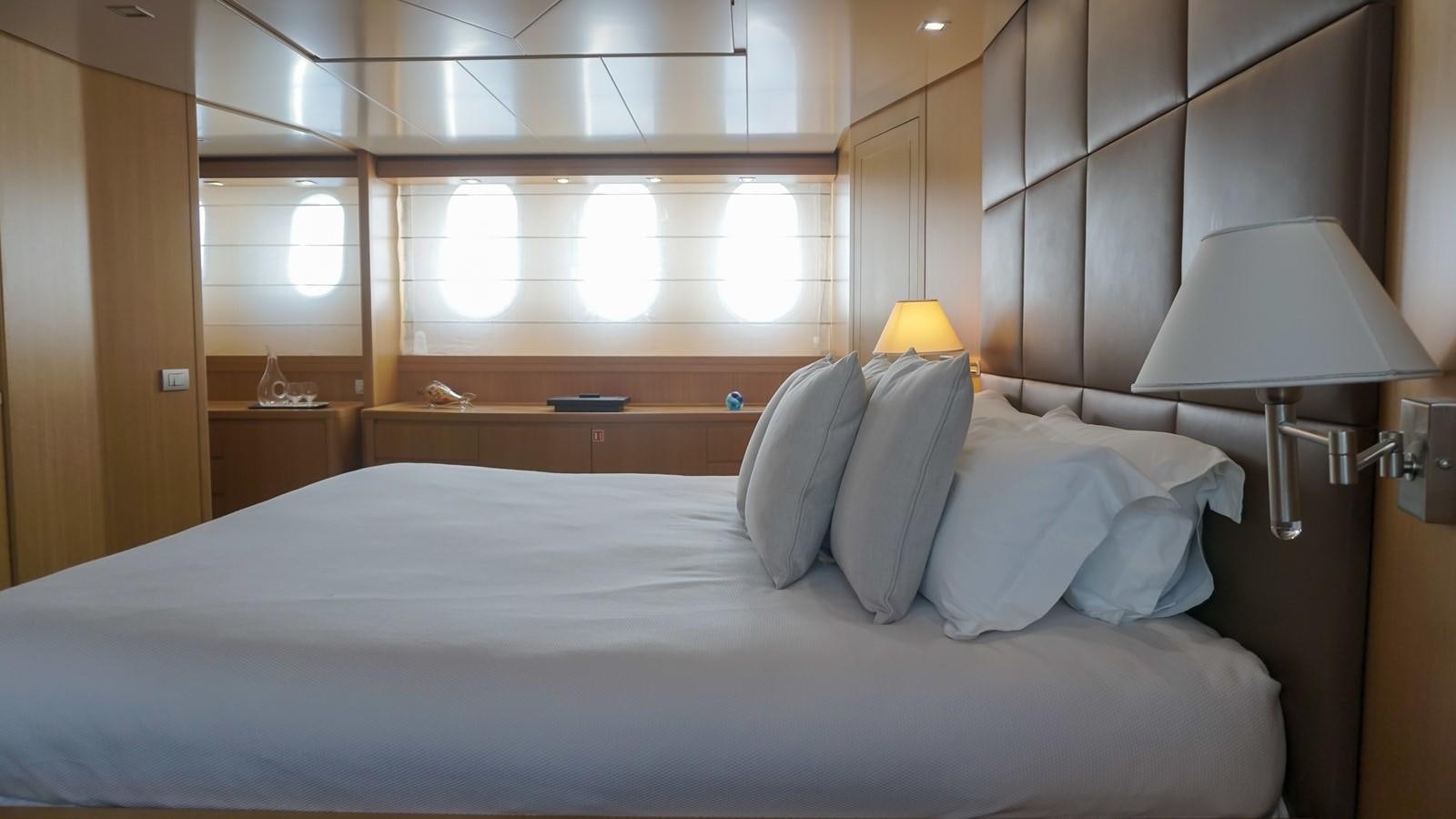 a bed with a white comforter and a lamp on it aboard PETRUS Yacht for Sale