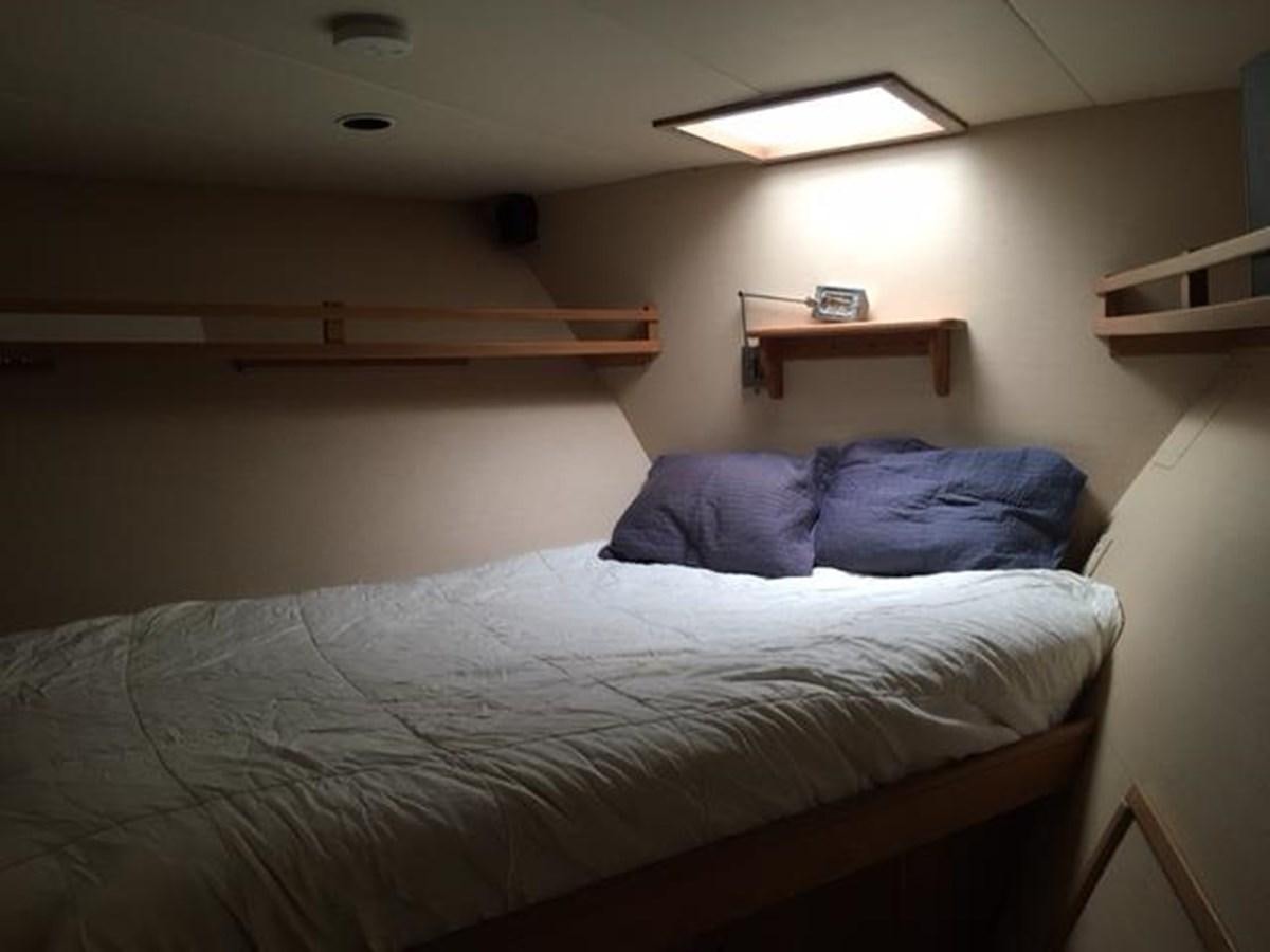 a bed with a white sheet and a wooden shelf aboard VICTORY Yacht for Sale