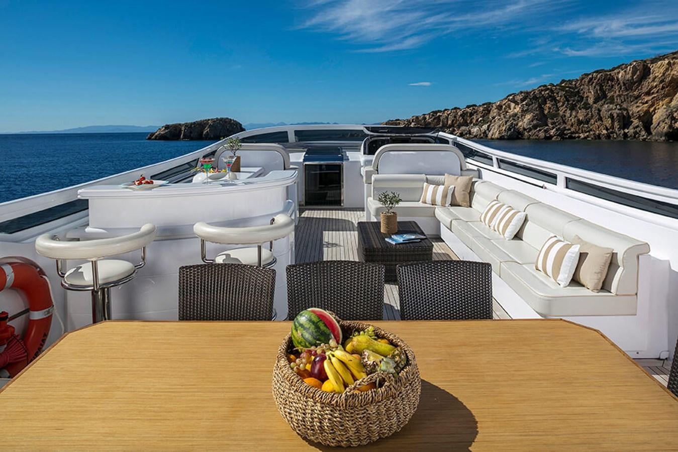 a table with chairs and a basket of fruit on it aboard MAIORA 35 DP Yacht for Sale