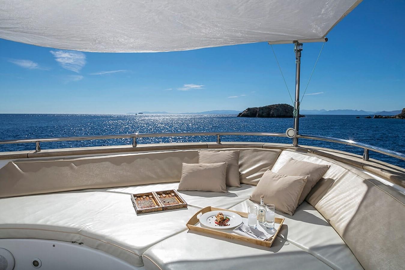 a bed with a white bed spread and a white table with a white cloth and a blue sky aboard MAIORA 35 DP Yacht for Sale