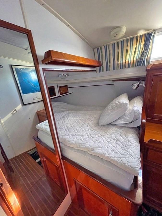 a bed with a pillow and a television on the wall aboard SIROCCO Yacht for Sale