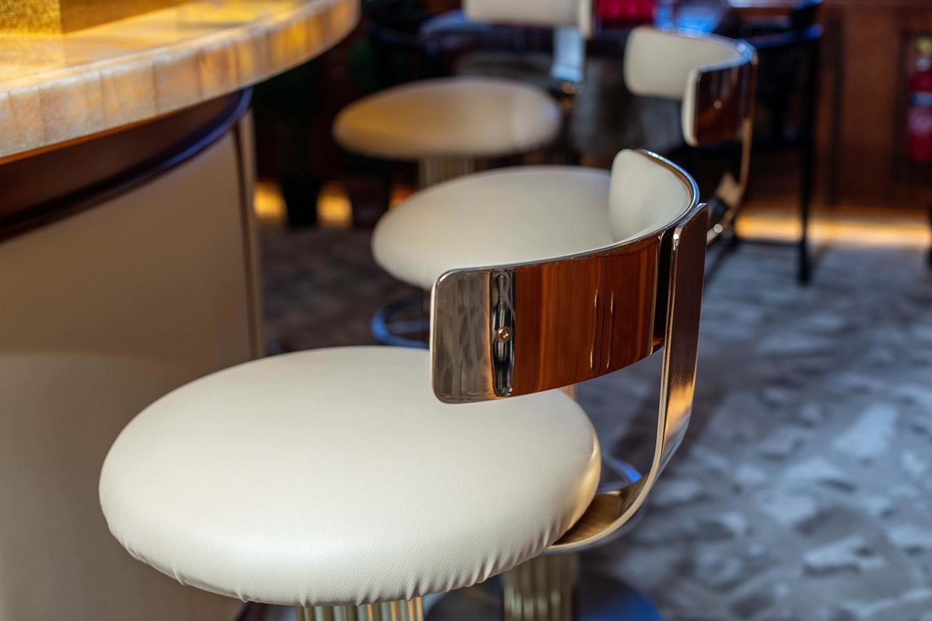 a white round table with a black chair and a white round table with chairs and a gray tiled aboard WILDE WHALE Yacht for Sale