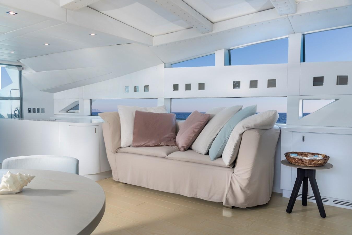 a white couch with a table and chairs in a room with white walls aboard BLUE PRINCESS STAR Yacht for Sale