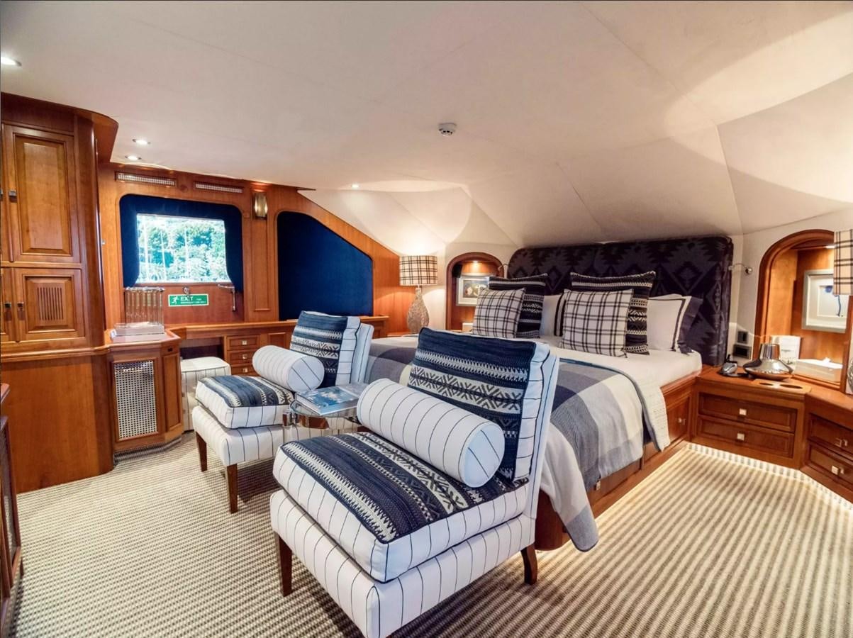 a bedroom with a bed and a chair aboard CHARISMA Yacht for Sale