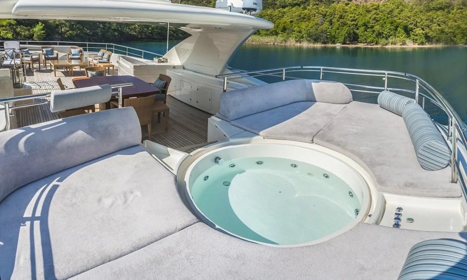 a pool with a lounge chair and a table and chairs on the side aboard ARIELA Yacht for Sale