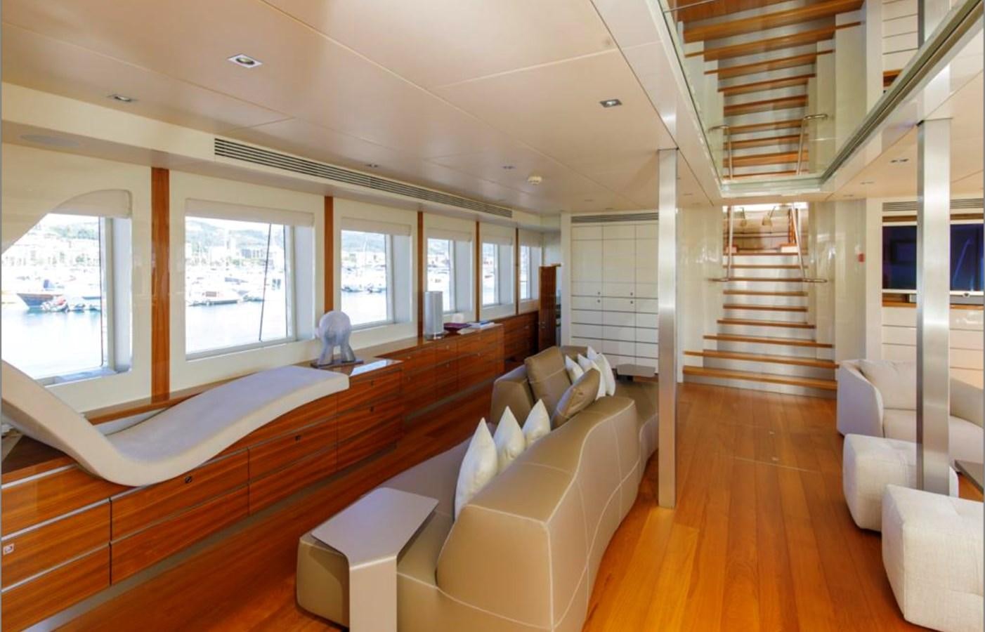 a room with a wood floor and white couches aboard BASMALINA II Yacht for Sale