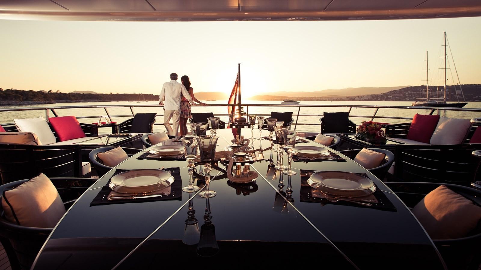 a large table with chairs and a couple of people on it aboard STEP ONE Yacht for Sale