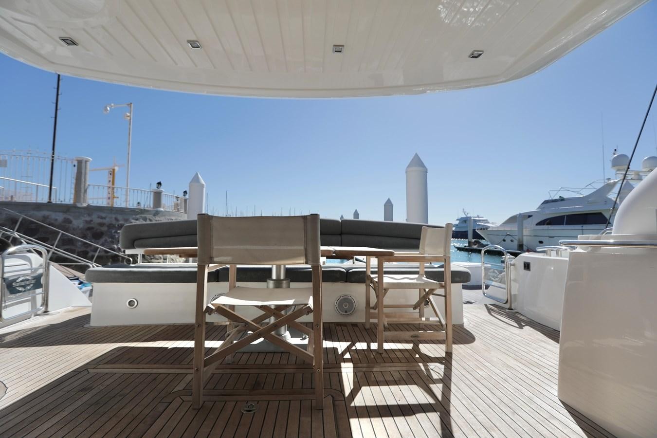 a deck with a table and chairs on it aboard CAPRICHO II Yacht for Sale