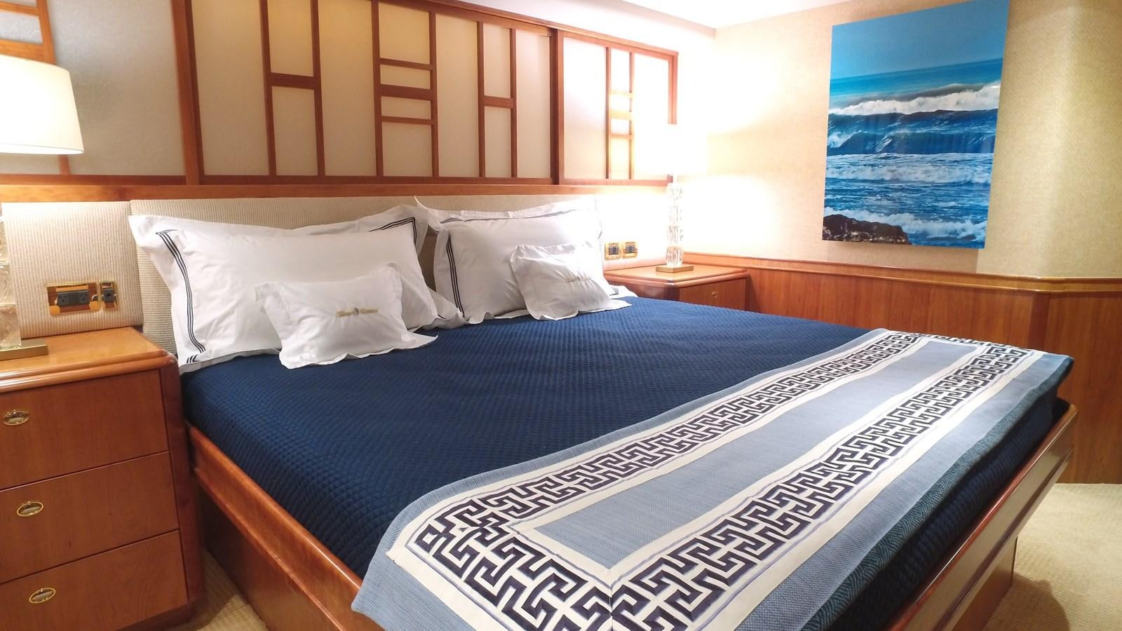 a bed with a blue and white comforter and a blue painting on the wall aboard SHORT GAME Yacht for Sale