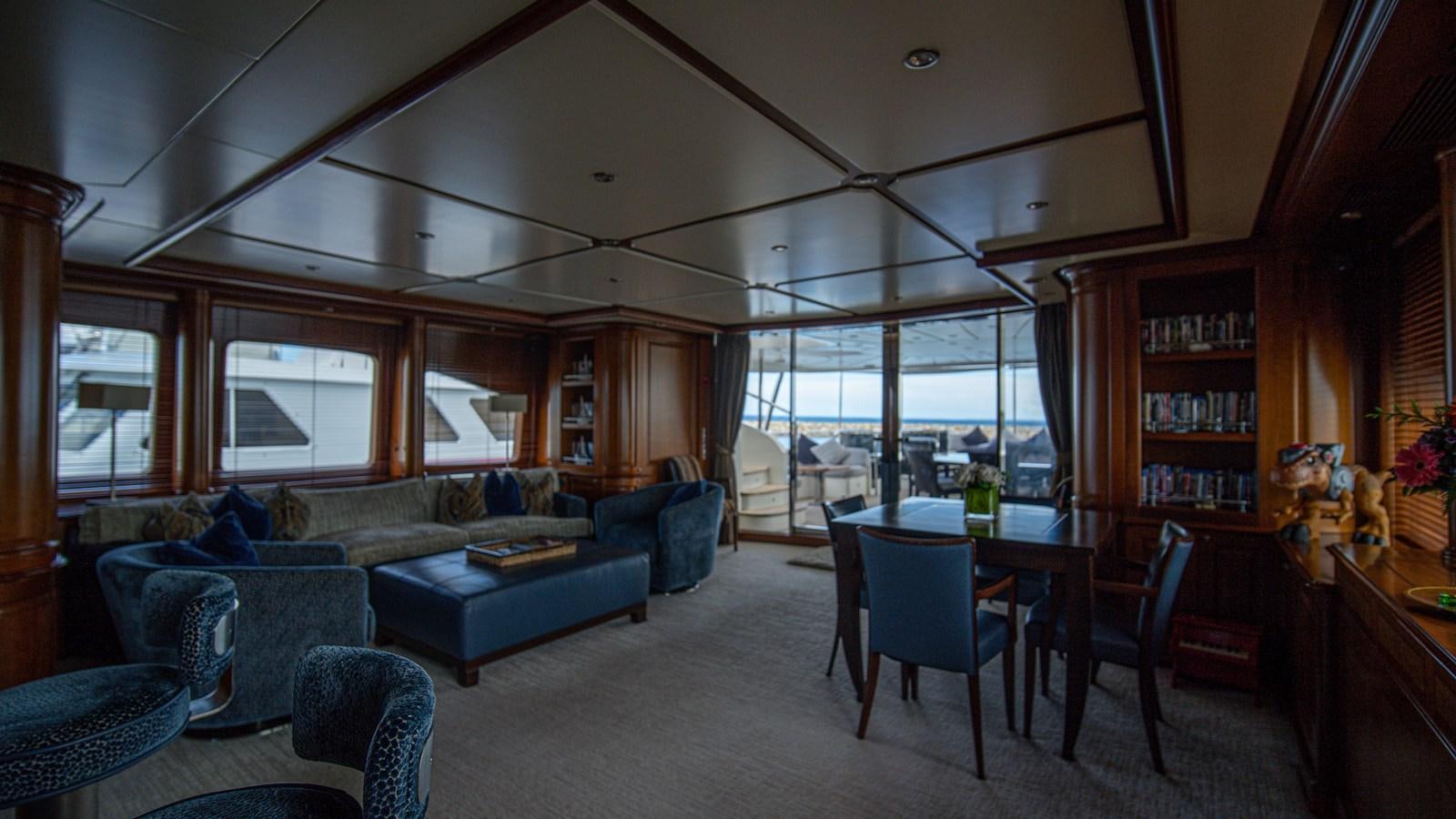 a living room with a blue couch and a large window aboard ORINOKIA Yacht for Sale