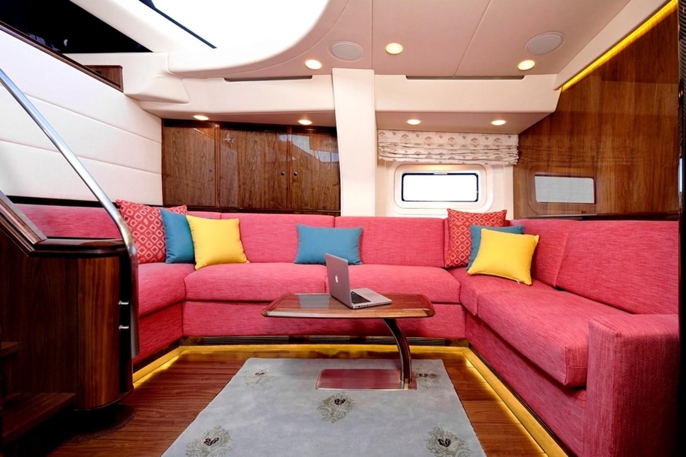 a living room with a red couch and a laptop on a coffee table aboard SERAFIM Yacht for Sale