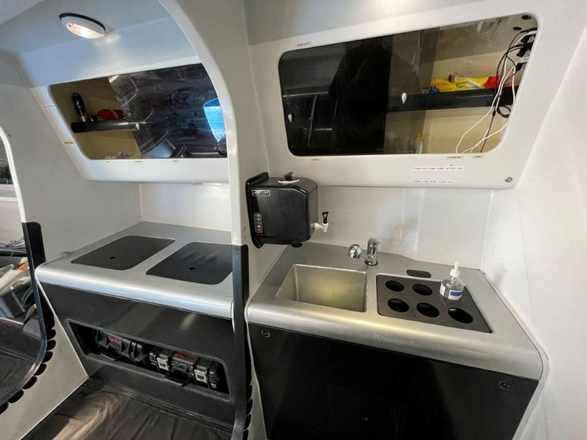 a small white kitchen with a sink and stove aboard BLACK JACK IV Yacht for Sale