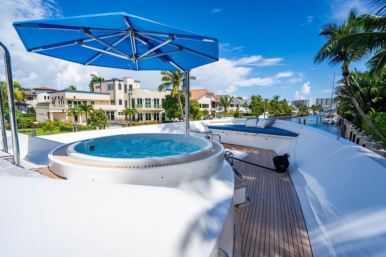 a deck with a pool and a building in the background aboard YOLO Yacht for Sale