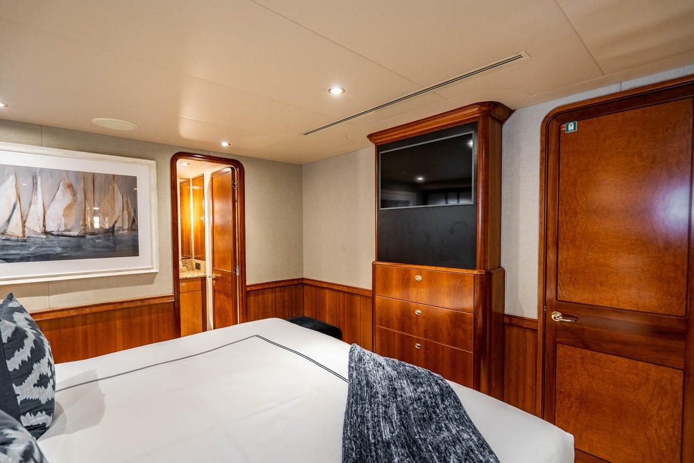 a bedroom with a bed and a wood cabinet aboard YOLO Yacht for Sale